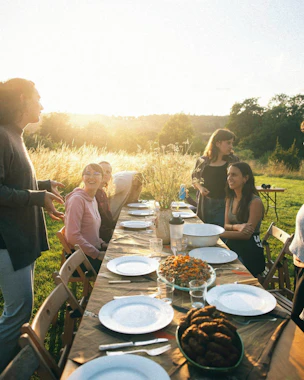 Young people sat around a table outside at dusk